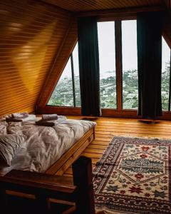 a bedroom with a bed and a rug and windows at Ayliya bungalow in Trabzon