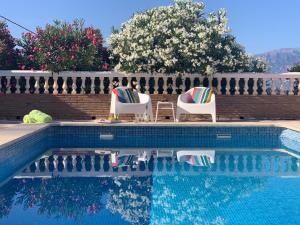 Iznate的住宿－Casa Anhelando Andalucia - Een villa prachtig op een heuveltop met magnifiek uitzicht nabij dorp en strand，一个带两把草坪椅的游泳池,围栏旁