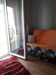 an orange couch in a room with a sliding glass door at Apartman Katarina in Vranje