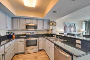a kitchen with white cabinets and stainless steel appliances at Oceanfront Myrtle Beach Condo with Pools and Hot Tubs in Myrtle Beach