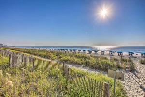 a beach with umbrellas and the ocean at Oceanfront Myrtle Beach Condo with Pools and Hot Tubs in Myrtle Beach