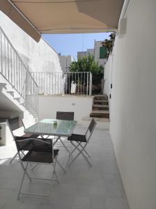 einen Glastisch und Stühle auf einer Terrasse mit Treppe in der Unterkunft Dimora Collina 3 in Sannicola