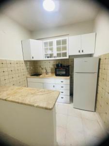 La cuisine est équipée de placards blancs et d'un réfrigérateur blanc. dans l'établissement ΑKASTI STUDIOS, à Olympiakí Aktí