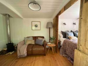 una camera con divano, letto e tavolo di Cornwall Woodland Shepherd's Hut Deirdres Hut a Bodmin