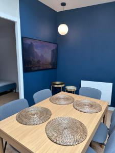 uma mesa de madeira com quatro cadeiras e uma parede azul em Le loft du chapitre em Saint-Brieuc