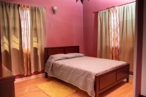a bedroom with a bed with pink walls and curtains at Pawadi Nou in Augier