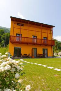 a yellow house with a balcony and a yard at Apartments Maligoj in Tolmin