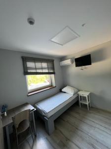 um pequeno quarto com uma cama e uma janela em Noclegi Europol em Siemianowice Śląskie