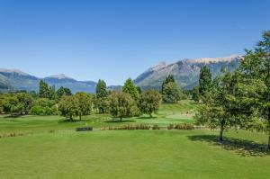 a view of a park with mountains in the background at Arelauquen Lodge, a Tribute Portfolio Hotel in San Carlos de Bariloche