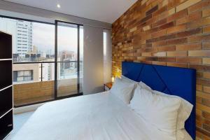 - une chambre avec un mur en briques et un grand lit dans l'établissement 812 Elevated Escape Loft, à Bogotá
