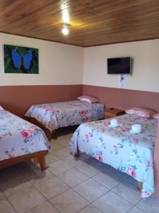 Habitación con 2 camas y TV en la pared. en Hotel La Puesta Del Sol B&B, en Monteverde