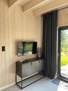 Stodoły na Fali في Sławoszynko: غرفة معيشة مع تلفزيون في جدار خشبي
