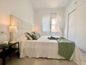 a white bedroom with a bed with a window at Golden Coast Calafell in El Vendrell