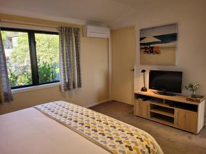 a bedroom with a bed and a flat screen tv at Hazelwood Mapua in Mapua