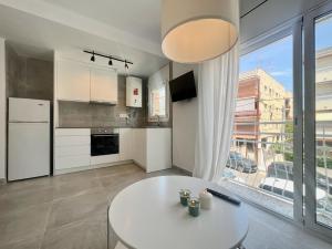a kitchen with a white table and a large window at Golden Coast Calafell in El Vendrell