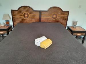 - un grand lit avec une serviette jaune et blanche dans l'établissement Villa Lovely, à Saint-François