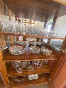 uma prateleira com pratos, taças e copos. em Vila beija-flor prime / apt 02 em Mucugê