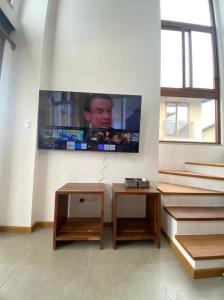 sala de estar con 2 mesas y TV en la pared en Vila beija-flor prime / apt 02, en Mucugê