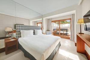 a bedroom with a large white bed and a window at Gecko Hotel & Beach Club, a Small Luxury Hotel of the World in Playa Migjorn