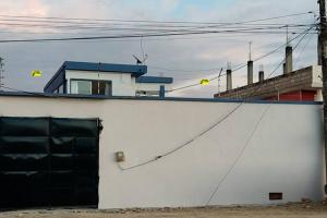 una pared blanca con una puerta negra y un edificio en Amplia casa en Tonsupa con piscina privada y WIFI, en Tonsupa