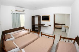 uma sala de estar com duas camas e uma televisão em CASA DA ZEZÉ Pousada & Hotel ITABORAÍ em Itaboraí