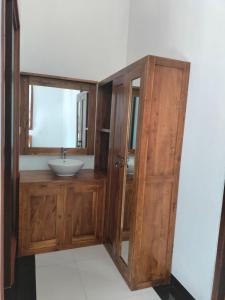 baño con lavabo y armario de madera en Baruna Sari Villa en Ubud