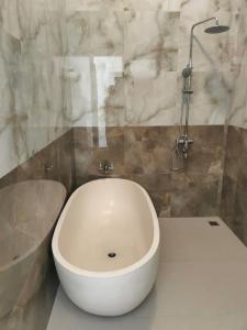 Baruna Sari Villa في أوبود: حمام مع حوض استحمام أبيض ومغسلة