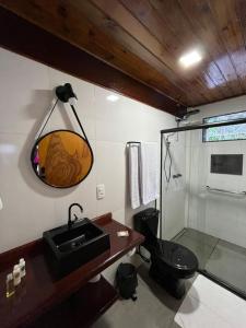 a bathroom with a black toilet and a sink at Pousada Rosa dos Ventos Kchu in Cachoeiras de Macacu