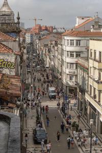 una strada trafficata della città con persone, auto e edifici di Travel & Live Porto Hostel a Porto