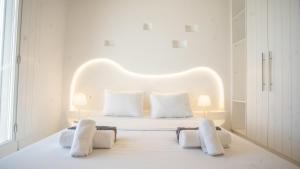 Dormitorio blanco con cama blanca y almohadas blancas en Elia Spirit Villas and Suites by Live&Travel, en Playa de Elia