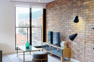 a living room with a tv and a brick wall at 902 Cityscape Loft in Bogotá