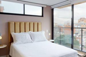 a bedroom with a white bed and a large window at 902 Cityscape Loft in Bogotá