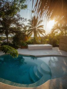 a large swimming pool in a yard with palm trees at Casa La Bomba in Puerto Escondido