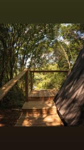 a wooden bridge in the middle of a forest at Chalé da Roça - Garibaldi in Garibaldi