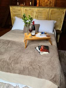 a bed with a table with a magazine and a bottle of wine at Chalé da Roça - Garibaldi in Garibaldi
