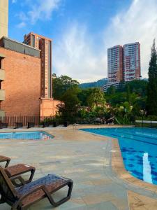 a swimming pool with two chairs and buildings at Apartamento luxury en sabaneta in Sabaneta