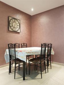 une table à manger avec des chaises et une horloge murale dans l'établissement appartement Islane G26, à Agadir