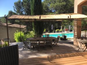 a patio with a table and chairs and a pool at Chambres d'hôtes La Manola in Rognes