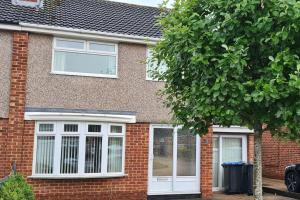 a brick house with white windows and a tree at Entire Home in Middlesbrough