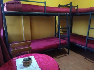 a room with two bunk beds and a table at Hostal Alejandra in Sucre