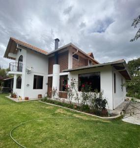 una casa blanca con césped delante en Casa de campo Guano Ecuador, en Riobamba