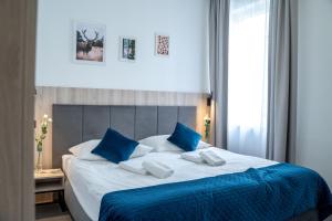 a bedroom with a large bed with blue and white pillows at Hotel Alpin in Szczyrk