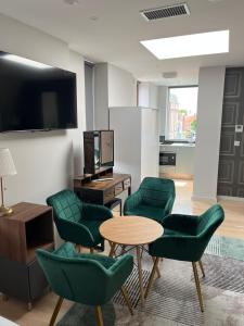 ein Wohnzimmer mit grünen Stühlen, einem Tisch und einem TV in der Unterkunft Merrion Square Studios in Dublin