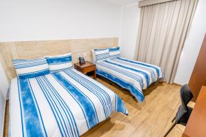 1 dormitorio con 2 camas con rayas azules y blancas en Hotel Pacific Blue Mazatlan en Mazatlán