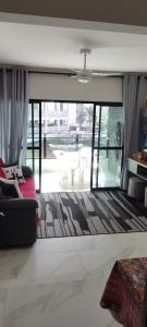 uma sala de estar com um sofá e uma grande janela em Apartamento Guarujá Astúrias no Guarujá