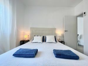 a white bed with two blue pillows on it at GOLDEN COAST CALAFELL 2 in El Vendrell