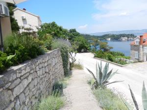 uma parede de pedra e uma estrada ao lado de um corpo de água em Apartments and rooms with parking space Sobra, Mljet - 18465 em Babino Polje