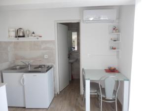 uma cozinha com um lavatório e uma mesa com cadeiras em Apartments and rooms with parking space Sobra, Mljet - 18465 em Babino Polje