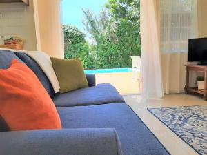 a living room with a blue couch and a large window at Vacation Home with Private Pool in Jolly Harbour