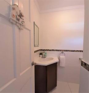 a white bathroom with a sink and a mirror at Vacation Home with Private Pool in Jolly Harbour